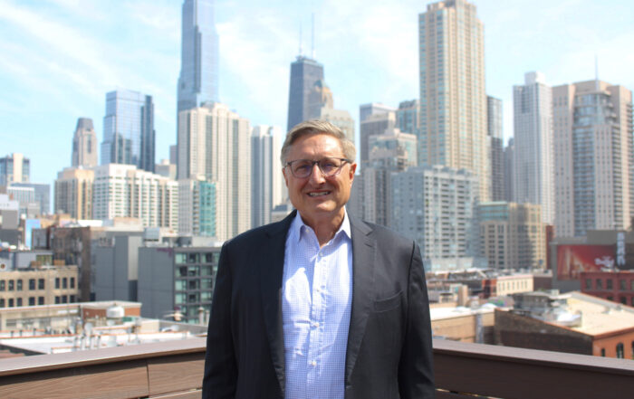 AMOpportunities new CEO John Danaher poses on a rooftop, the Chicago skyline behind him